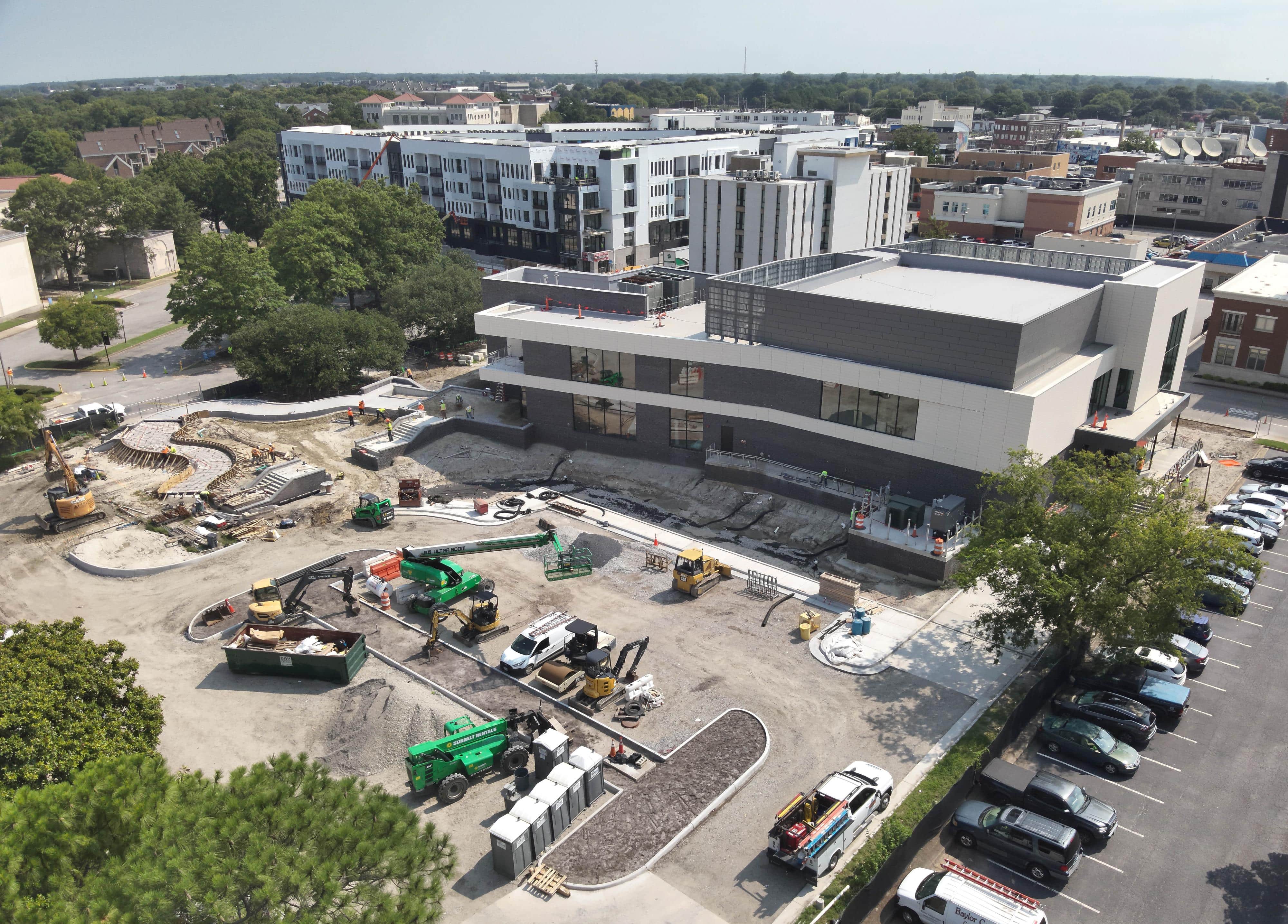 Aerial view of Chrysler Museum. Gray building with large parking lot of gravel with construction equipment parked.